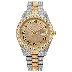 Detail of luxury iced-out watch showing gold Roman numerals and date window on diamond dial