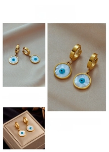 Detailed view of evil eye hoop earrings with white shell pendants and blue eye patterns