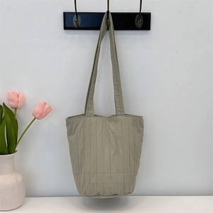 Primer plano de un bolso tote plisado verde sage con rayas verticales en un gancho