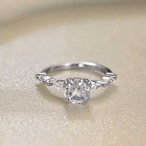 Macro shot of silver ring featuring a round brilliant center stone and marquise side diamonds