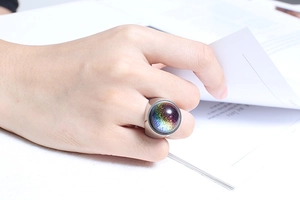 Close-up of a large dome ring with galaxy foil glass inlay worn while reading a book