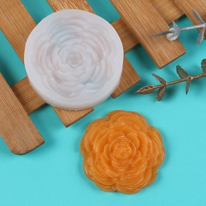 Macro detail of 3D peony flower silicone mold with finished orange floral scented candle