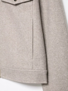 Detail of oatmeal soft wool jacket featuring side pocket design and premium fabric texture