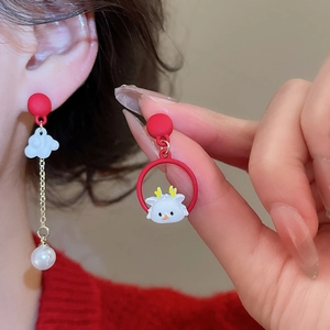 Macro detail of asymmetric New Year lion dance stud earrings with pearls and red enamel