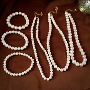 Détail de l'ensemble collier et bracelet en perles roses et blanches sur tissu