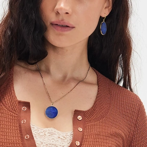Gros plan sur le collier et les boucles d'oreilles dorés avec lapis-lazuli bleu rond