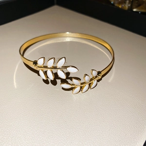 Detailed view of leaf-shaped ends with pearlescent enamel inlays on a gold open bangle