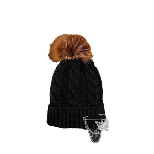 Black cable knit beanie with brown faux fur pom and butterfly pin chain accessory