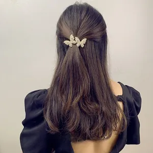 Close-up of golden butterfly hair clips with pearls on wavy brown hair