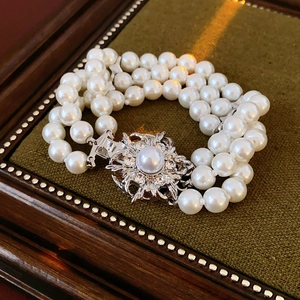 Macro shot of three-strand pearl bracelet with sparkling silver flower diamond clasp