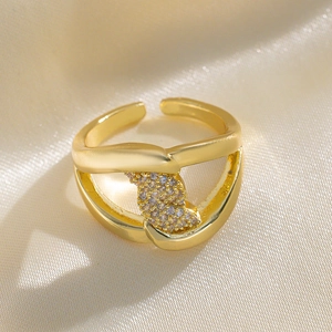 Elegant gold-plated open ring with twisted design and pavé cubic zirconia on silk background