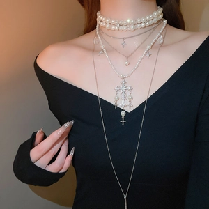 Macro detail of multi-layered pearl necklace featuring a sparkling diamond cross pendant