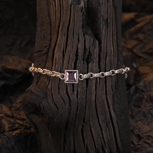 Detailed macro shot of vintage silver bracelet with square purple gemstone and relief patterns