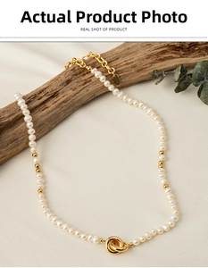 Detail of freshwater pearl choker featuring a golden double ring clasp on fabric