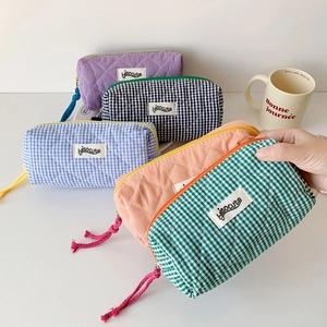 Quilted checkerboard pencil case detail featuring a colorful zipper pull and cotton texture