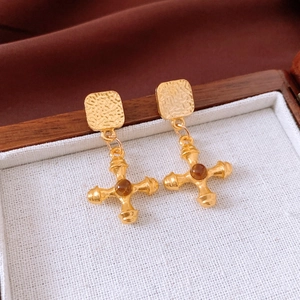 Detail of vintage gold cross earrings with hammered texture and amber bead in jewelry box
