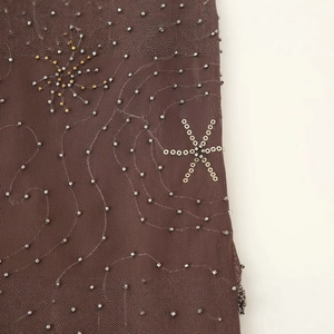Top in rete marrone con ricamo di perle e stelle di paillettes dorate in primo piano
