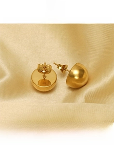 Detailed close-up of polished gold hemispherical stud earrings on silk background