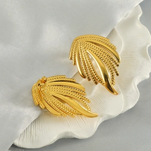 Macro shot of 18k gold plated stainless steel feather earrings with beaded textures