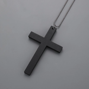 Detail shot of a matte black wooden cross pendant with a metal bead chain necklace