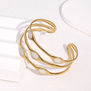Layered gold-plated open cuff bracelet with elegant white oval inlays and cutout design