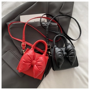 Chic red and black PU leather mini crossbody bags featuring large bow accents on a blazer