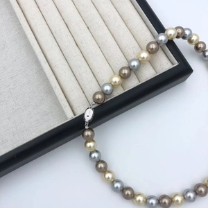 Detailed close-up of S925 clasp on vintage mixed-color pearl necklace in brown and gold