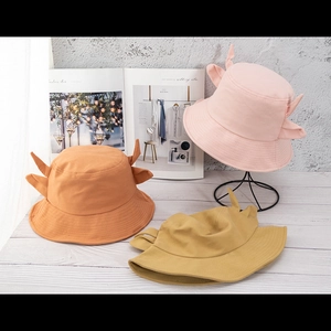 Cute cow print bucket hats with small horns in pink, orange, and ginger yellow colors