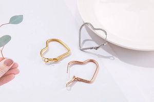 Detailed view of heart-shaped hoop earrings with snake chain texture in three metallic colors