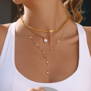 Gros plan de colliers multicouches dorés avec pendentifs en zircone portés par un mannequin