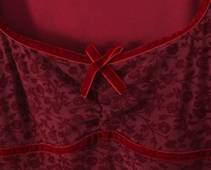 Detail of burgundy floral embroidery mesh fabric with velvet bow and lace trim