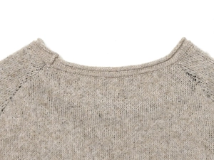 Close-up of beige knitted sweater with raglan sleeves and soft wool texture detail
