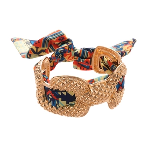 Metallic gold bangle with woven printed fabric knot and textured diamond rivet patterns