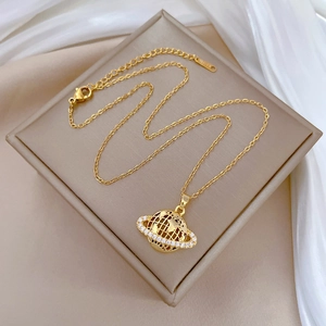 Detailed view of a gold globe pendant necklace with sparkling white zircons on silk