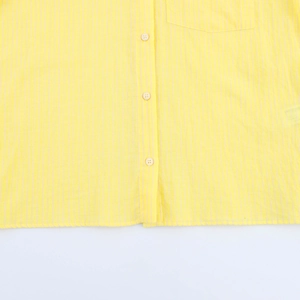 Dettaglio di una camicia a righe gialle che mostra la trama del cotone e i bottoni bianchi