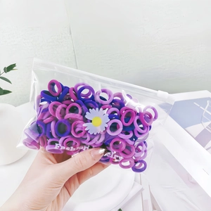 Close-up of purple elastic hair ties set in a daisy patterned zipper pouch for girls