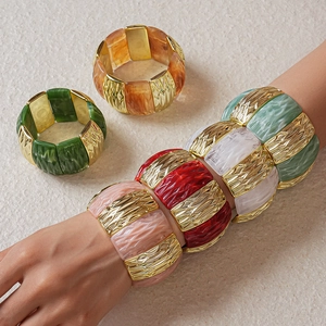 Detail of chunky acrylic stretch bracelets with gold textured metal blocks in various colors