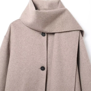 Detail of oatmeal wool coat featuring wrap-around collar and black button closure