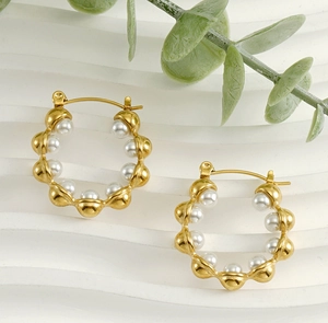 Detail view of 18k gold plated hoop earrings with white pearls on a display stand