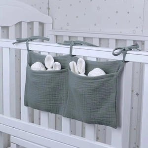 Detail of grey-green double-pocket cotton crib organizer with decorative ties on bed rail