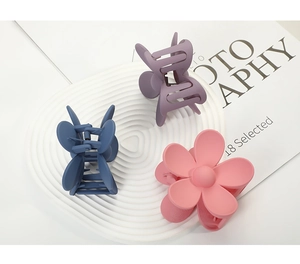 Detailed close-up of three matte flower hair claws in blue, purple and pink colors