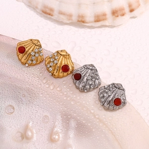 Macro shot of gold and silver shell-shaped earrings with red gemstones and crystals