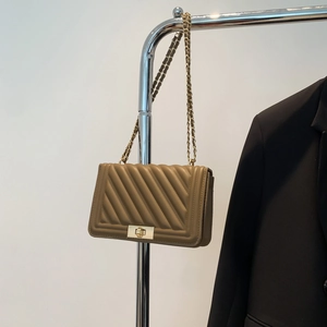 Detail of khaki chevron quilted shoulder bag with golden twist lock and chain strap