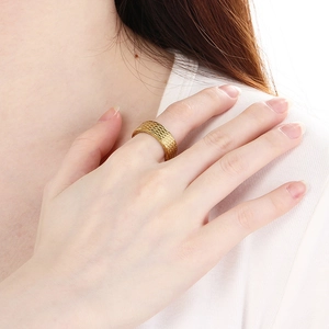 Detail of gold woven texture ring on hand showing intricate industrial grid pattern