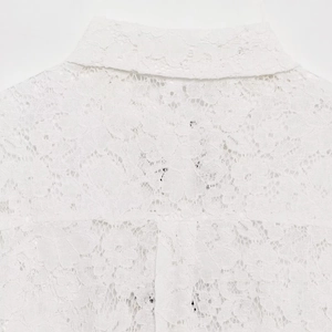Close-up of elegant white lace pattern and hollow texture on a women's fashion shirt