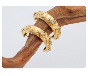 Macro view of gold sun and moon hoop earrings with crystal on a wooden branch