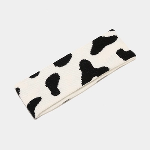 Close-up of soft black and white cow print knitted headband with plush winter texture