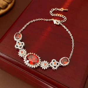Detailed shot of oval red gemstones and flower motifs on a silver bracelet over wood