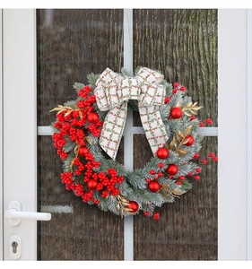 Close-up of a Christmas wreath with red berries and bow hanging on a white door