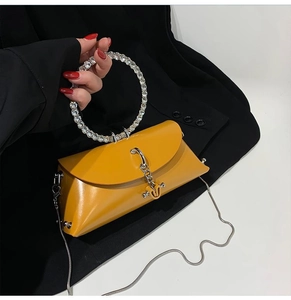 Macro shot of yellow handbag featuring a large diamond-encrusted circular metal handle